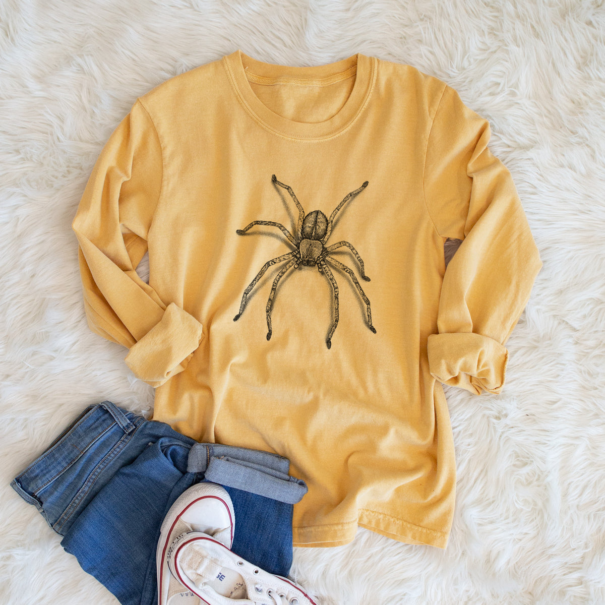 Golden wheat yellow Comfort Colors long sleeve shirt printed with a detailed black ink illustration of a huntsman spider with long legs spread, shown in a lifestyle photo.