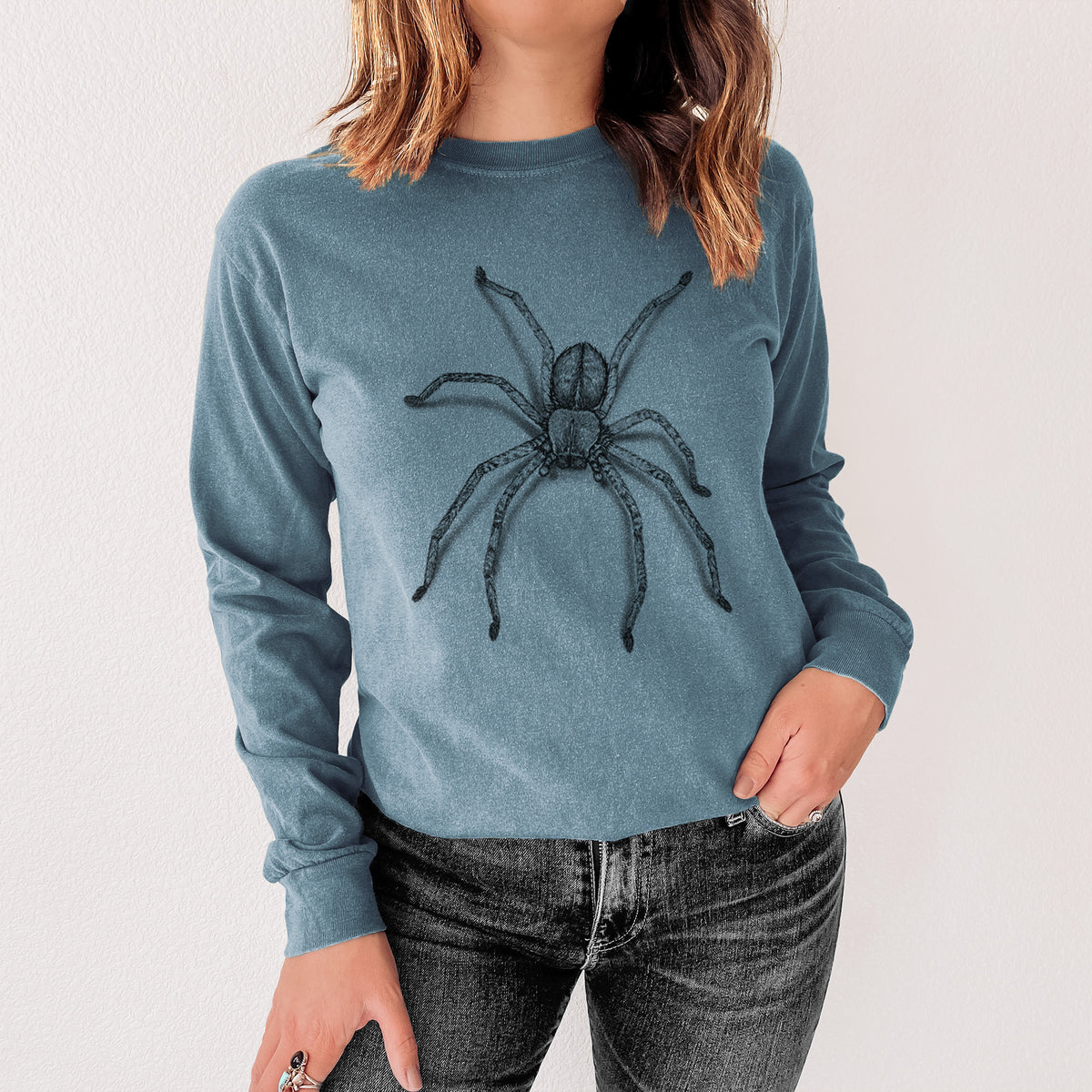Steel blue Comfort Colors long sleeve shirt printed with a detailed black ink illustration of a huntsman spider with long legs spread, shown in a lifestyle photo.