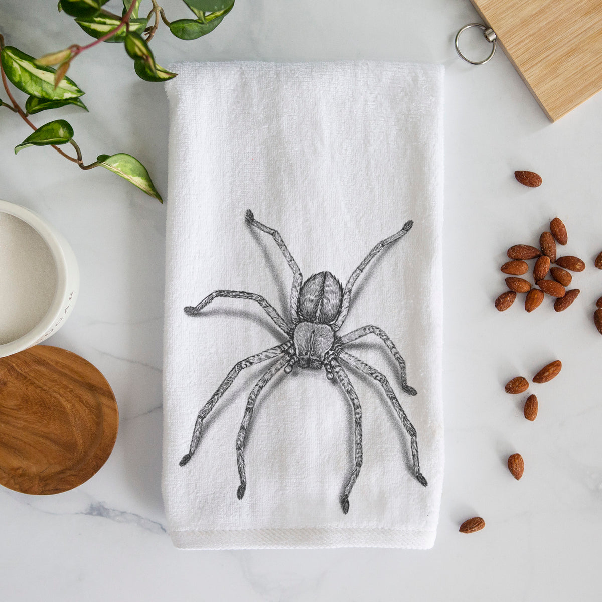 White hand towel printed with a detailed black ink illustration of a huntsman spider with long legs spread.