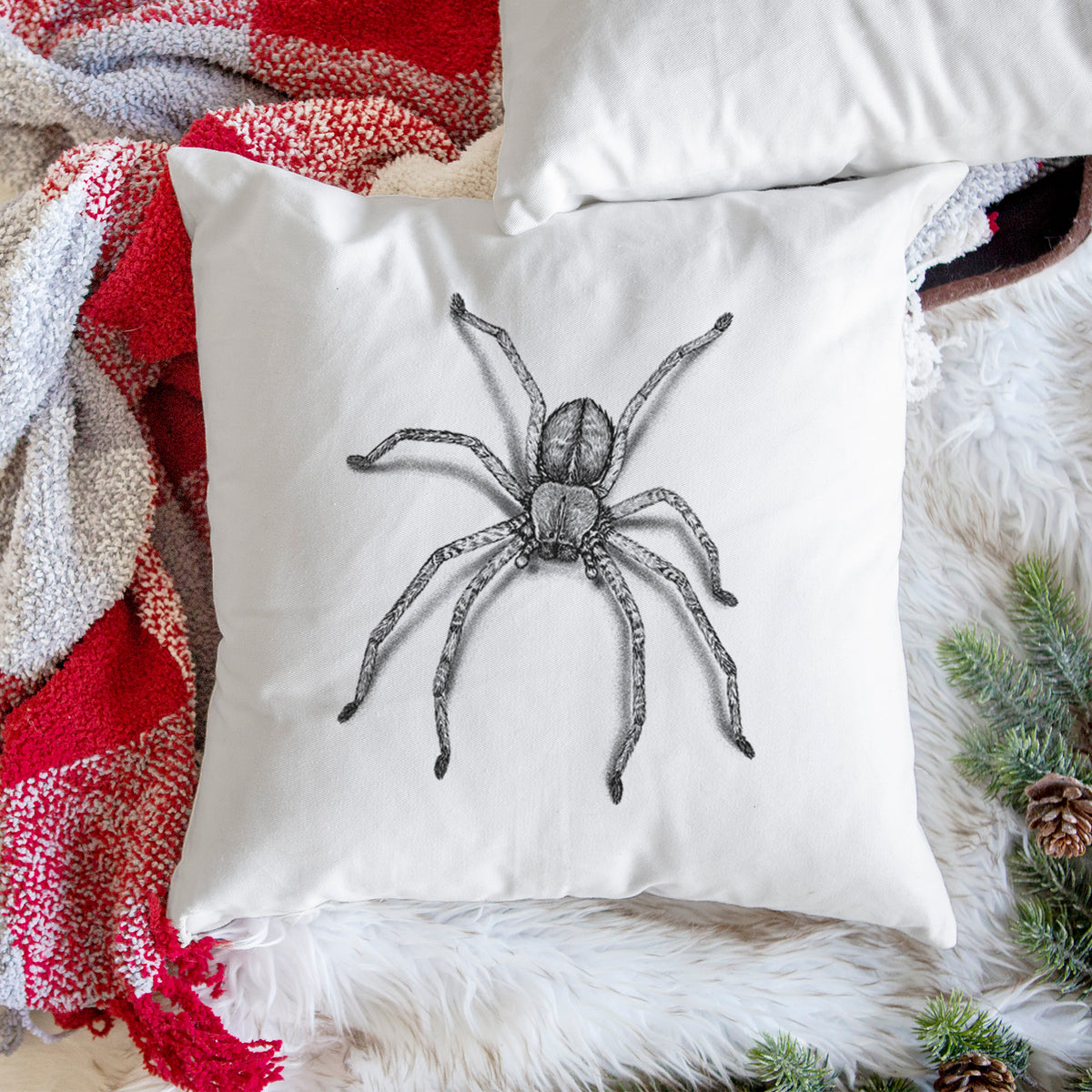 White pillow cover printed with a detailed black ink illustration of a huntsman spider with long legs spread, on a woven chair.