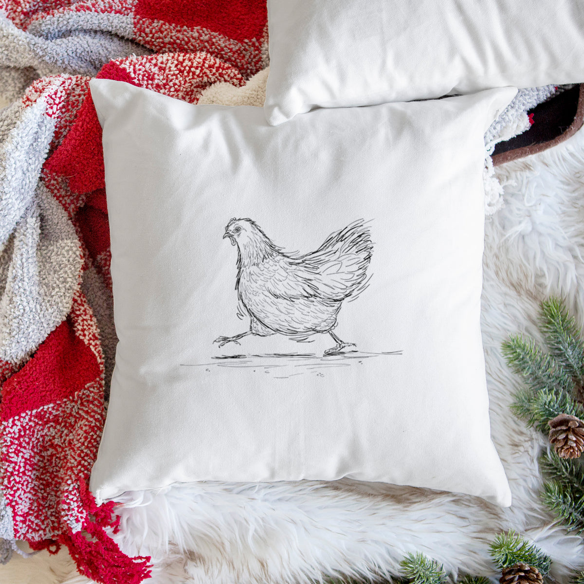 White pillow cover printed with a black ink sketch of a hen hurrying along, on a woven chair.