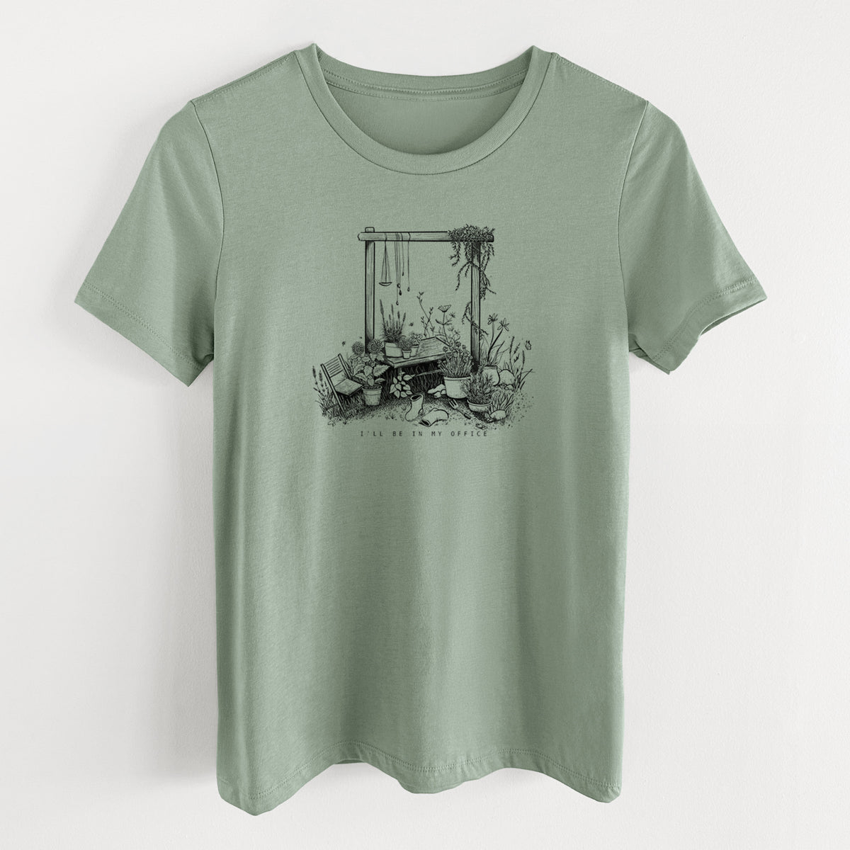 Sage green women's relaxed fit cotton t-shirt laid flat, printed with a black ink illustration of a garden gate arch surrounded by potted plants and flowers.