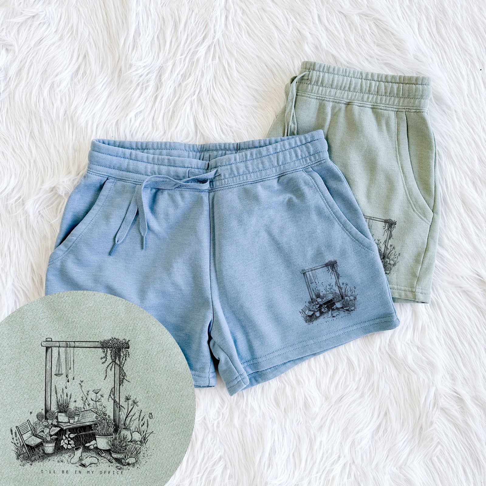 Two pairs of Cali Wave shorts in different colors printed with a black ink illustration of a garden gate arch surrounded by potted plants and flowers, with a close-up of the print.