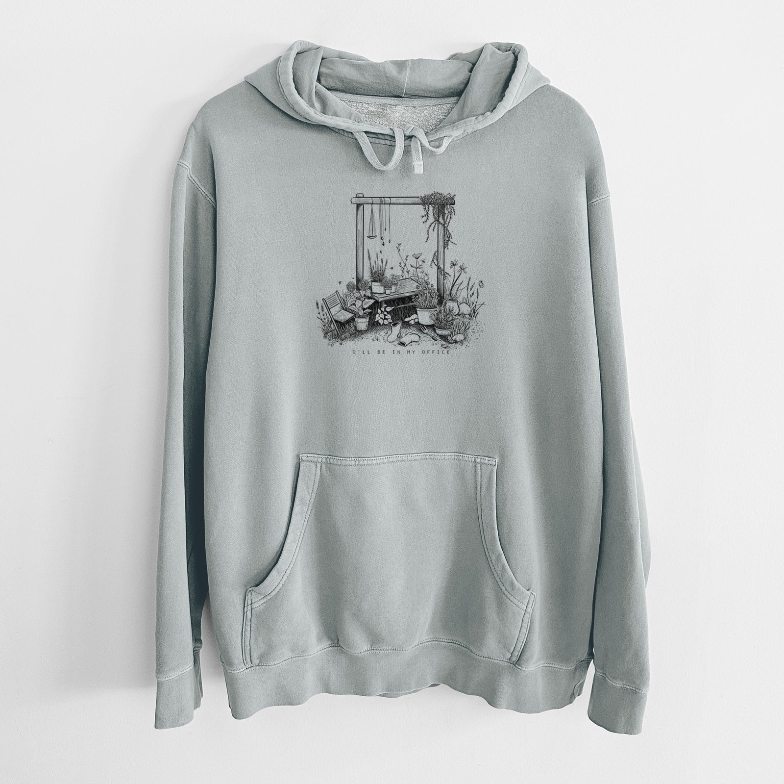 Sage green pigment dyed hoodie laid flat, printed with a black ink illustration of a garden gate arch surrounded by potted plants and flowers.