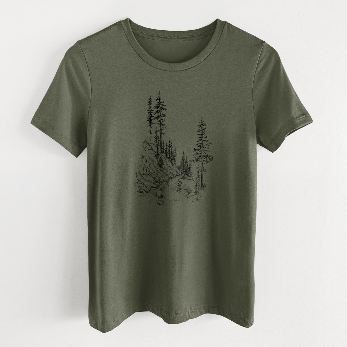 Military green women's relaxed fit cotton t-shirt laid flat, printed with a black ink illustration of a trail winding past tall pine trees and rocks into the woods.