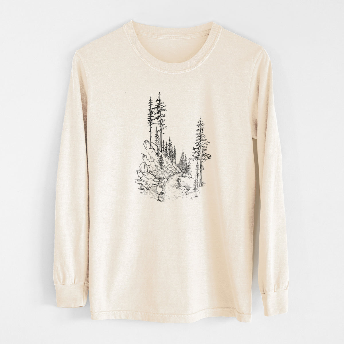 Ivory Comfort Colors long sleeve shirt laid flat, printed with a black ink illustration of a trail winding past tall pine trees and rocks into the woods.