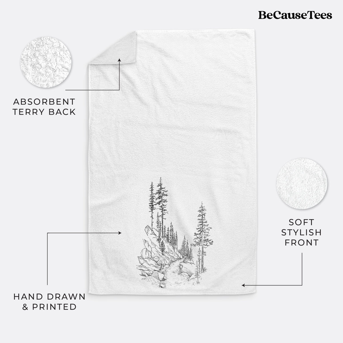 White hand towel printed with a black ink illustration of a trail winding past tall pine trees and rocks into the woods.