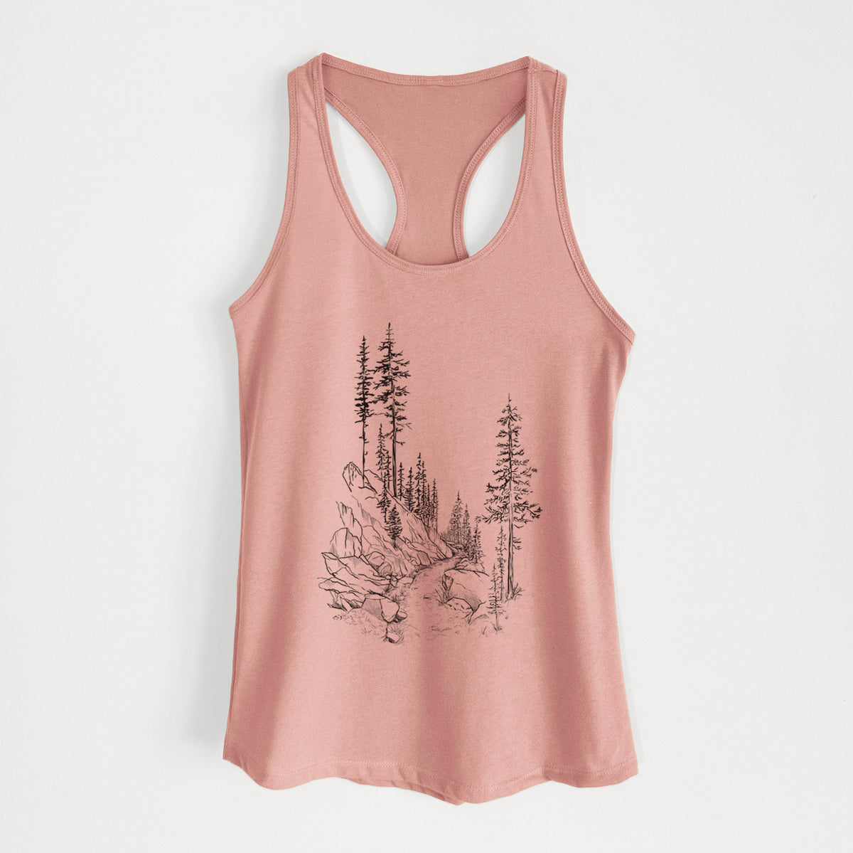 Desert pink women's racerback tank top laid flat, printed with a black ink illustration of a trail winding past tall pine trees and rocks into the woods.
