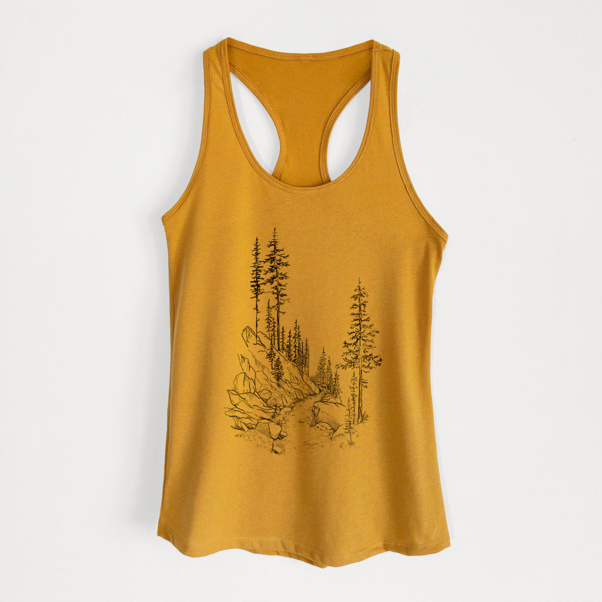 Gold women's racerback tank top laid flat, printed with a black ink illustration of a trail winding past tall pine trees and rocks into the woods.