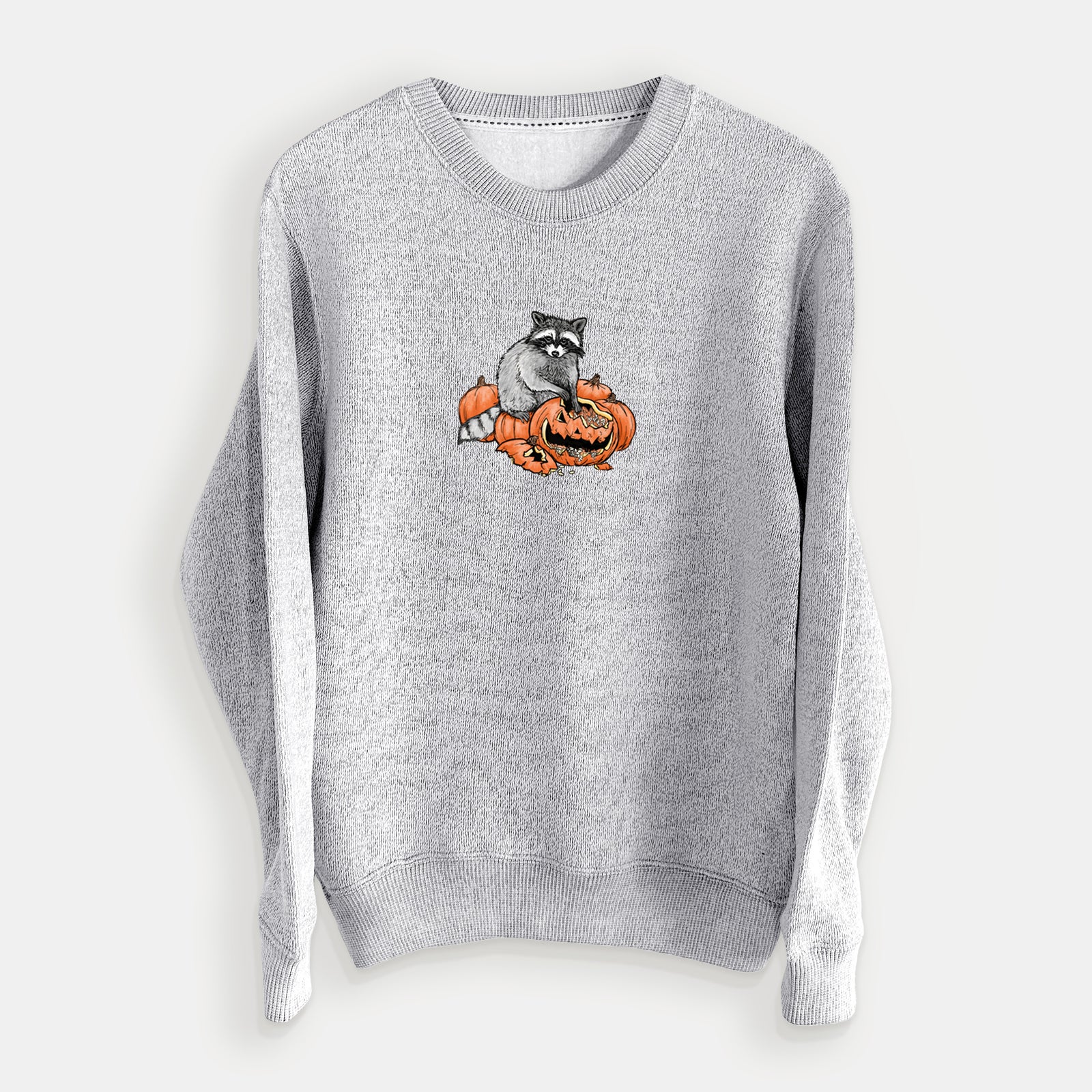 Salt and pepper knit sweatshirt laid flat, printed with a black ink raccoon peeking over carved orange jack-o'-lanterns.
