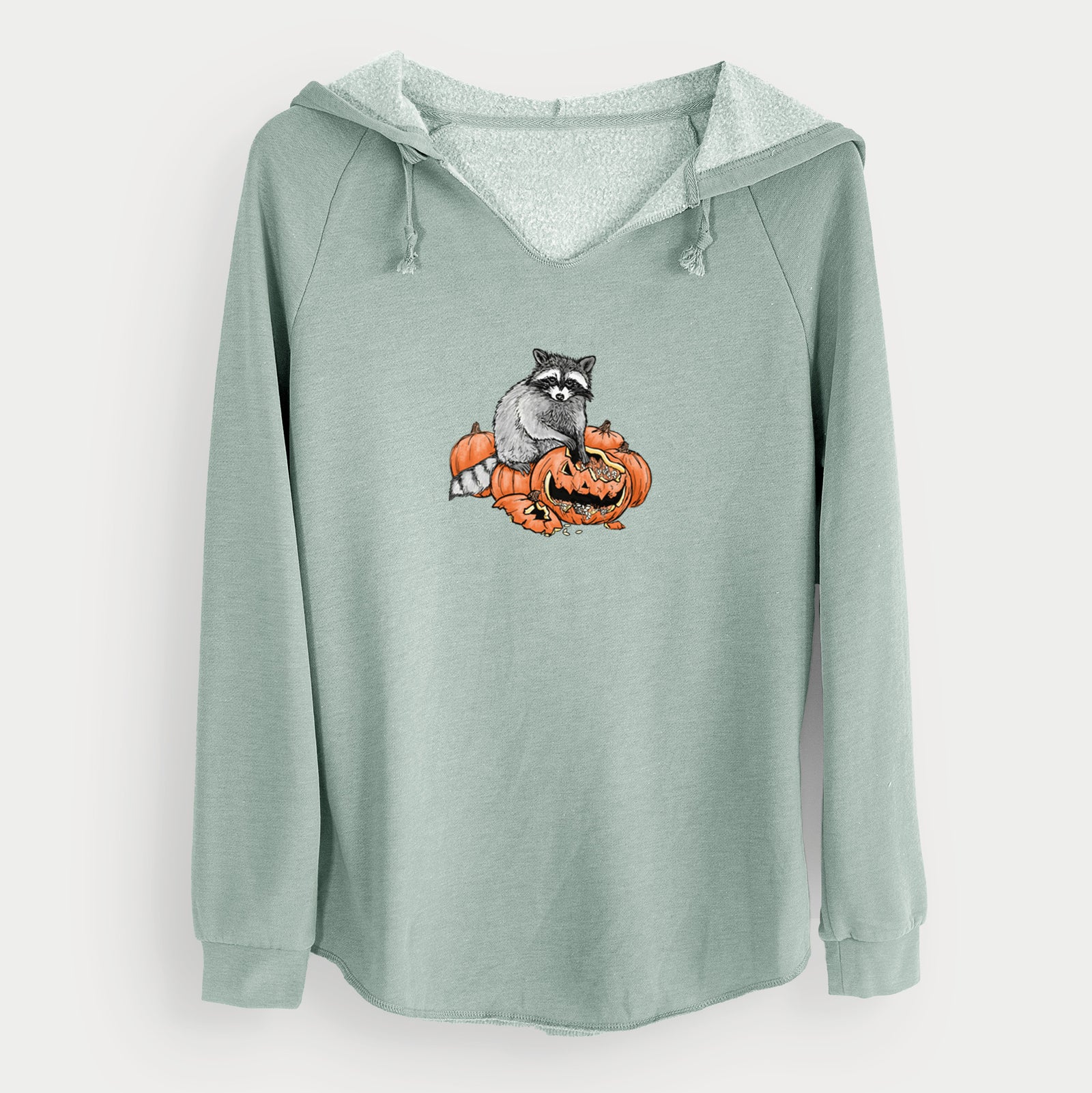 Sage green women's Cali Wave hooded sweatshirt laid flat, printed with a black ink raccoon peeking over carved orange jack-o'-lanterns.