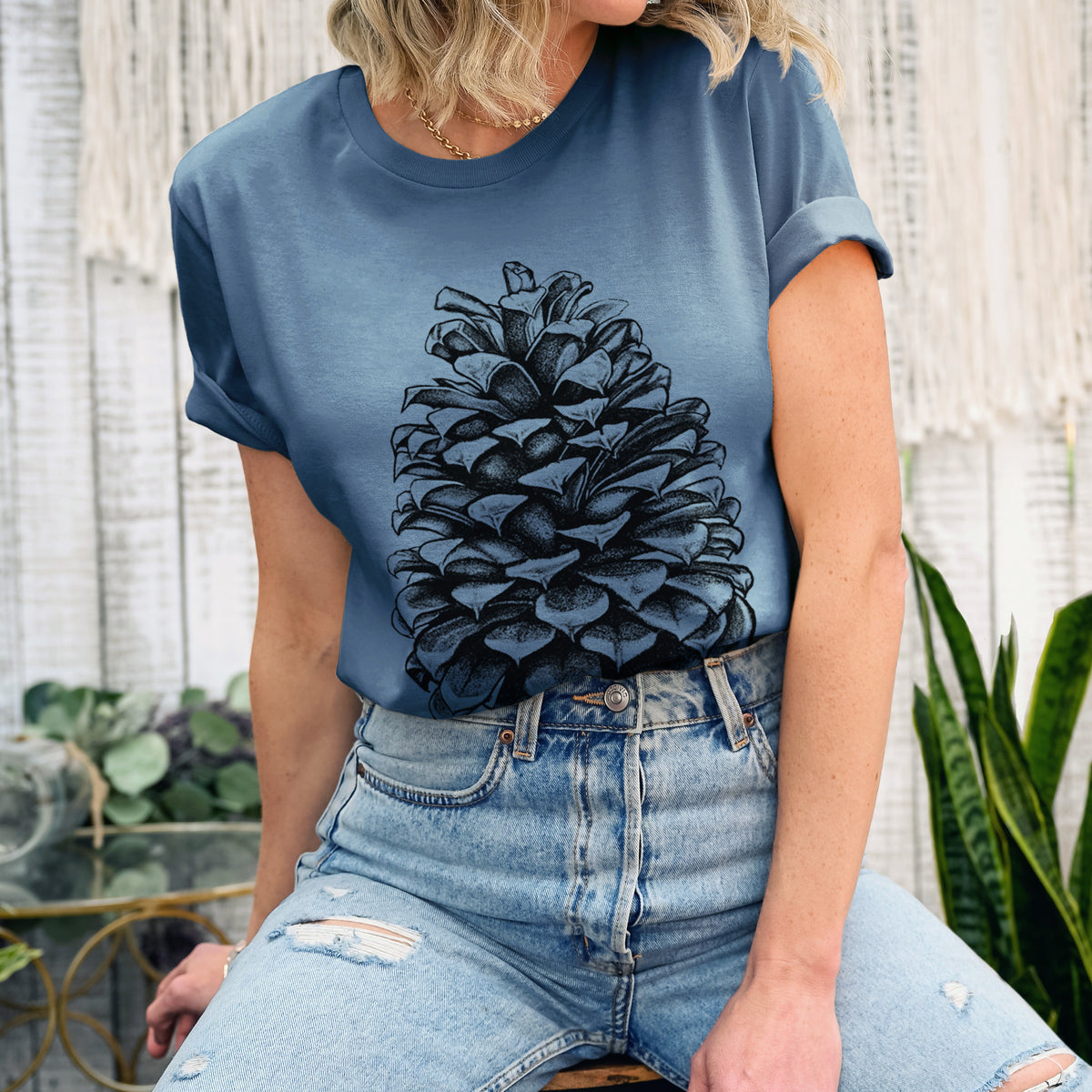Woman wearing a steel blue lightweight cotton t-shirt printed with a detailed black ink illustration of a large Jeffrey pine cone.