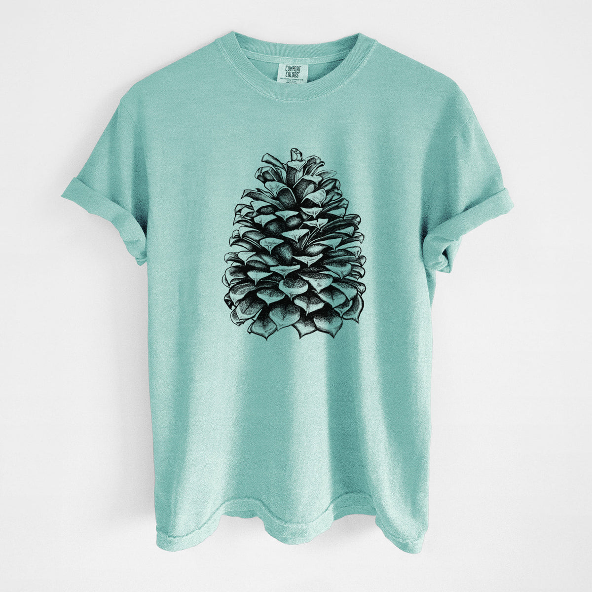 Chalky mint Comfort Colors t-shirt laid flat, printed with a detailed black ink illustration of a large Jeffrey pine cone.