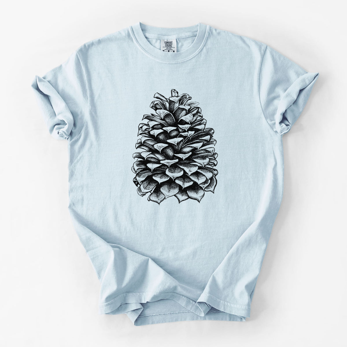 Chambray blue Comfort Colors t-shirt laid flat, printed with a detailed black ink illustration of a large Jeffrey pine cone.