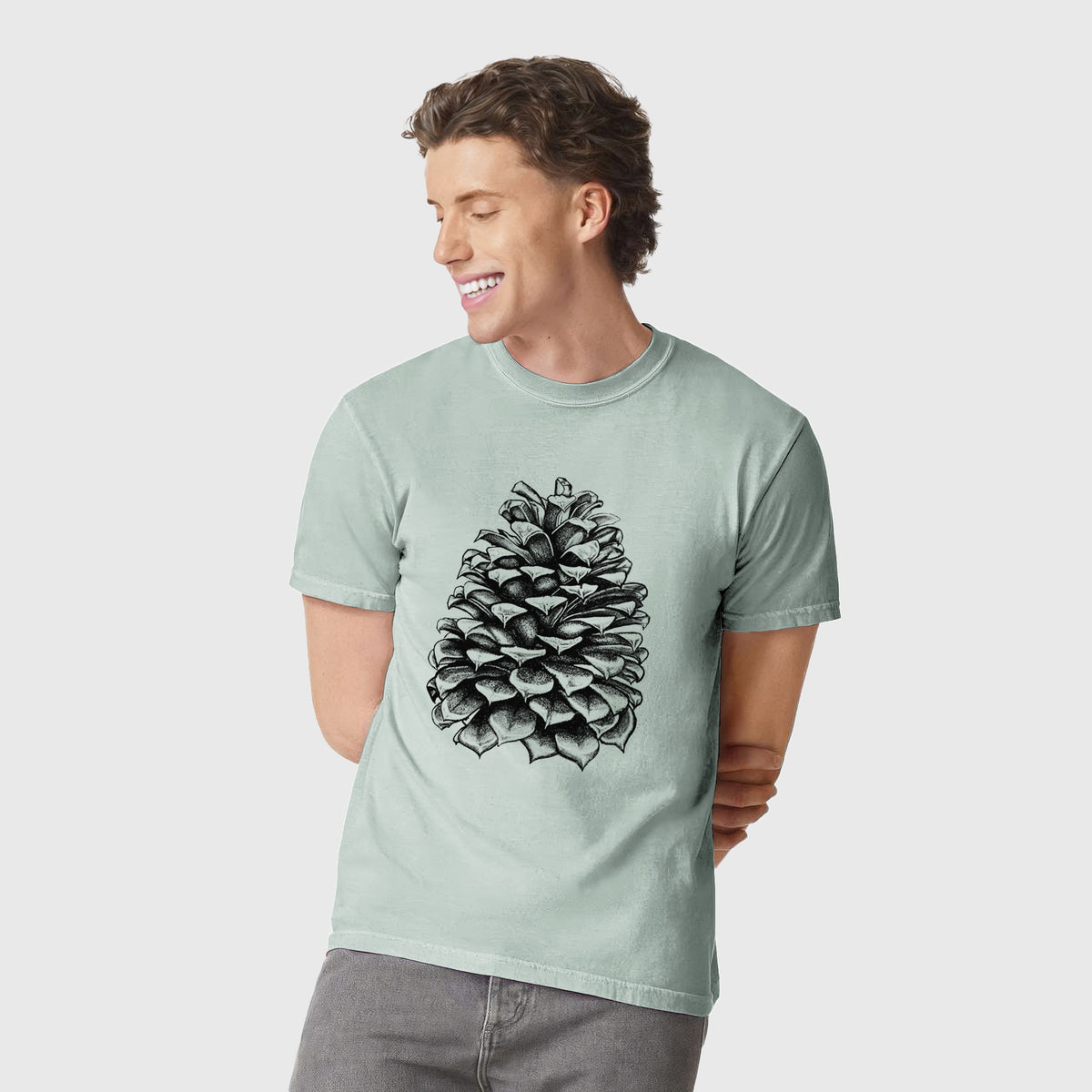 Man wearing a Comfort Colors t-shirt printed with a detailed black ink illustration of a large Jeffrey pine cone.