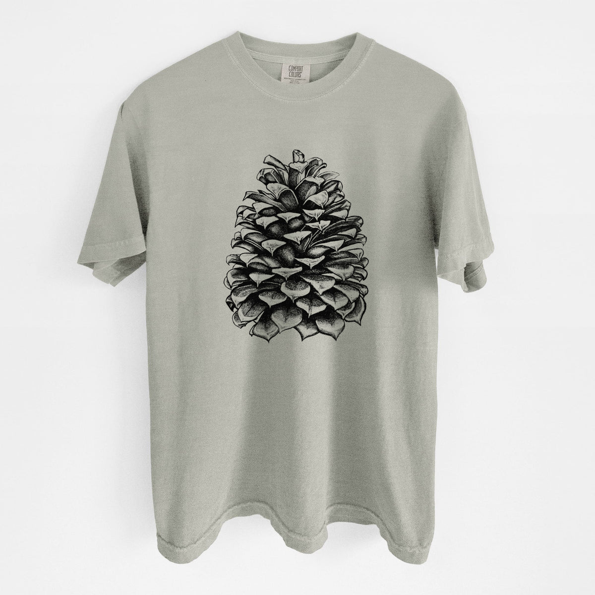 Sandstone beige Comfort Colors t-shirt laid flat, printed with a detailed black ink illustration of a large Jeffrey pine cone.