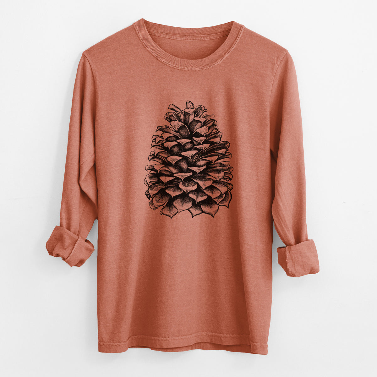 Yam burnt orange Comfort Colors long sleeve shirt laid flat with the cuffs rolled, printed with a detailed black ink illustration of a large Jeffrey pine cone.