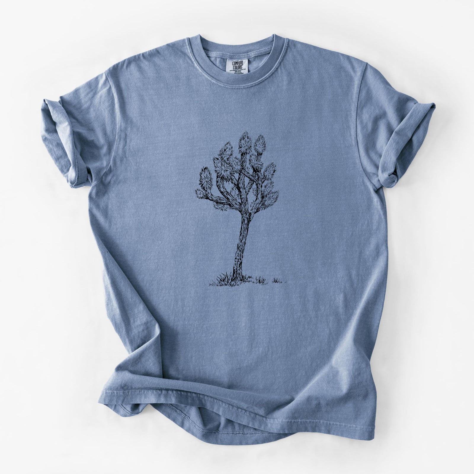 Blue jean Comfort Colors t-shirt laid flat, printed with a detailed black ink illustration of a Joshua tree.