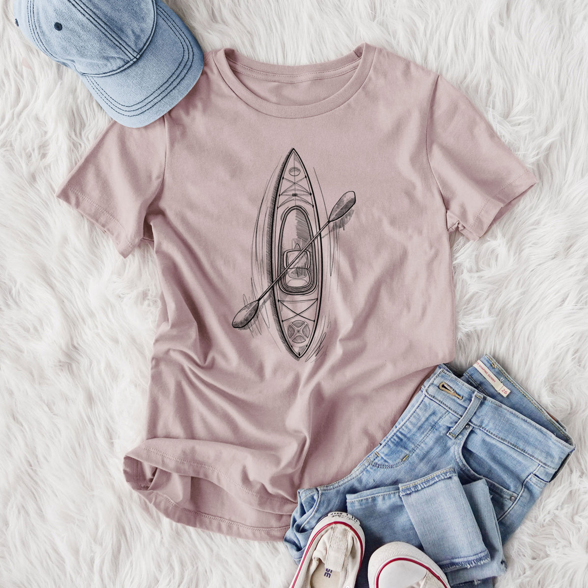 Women's relaxed fit cotton t-shirt printed with a black ink illustration of a kayak with a paddle, seen from above, styled flat on a white faux fur rug with jeans.