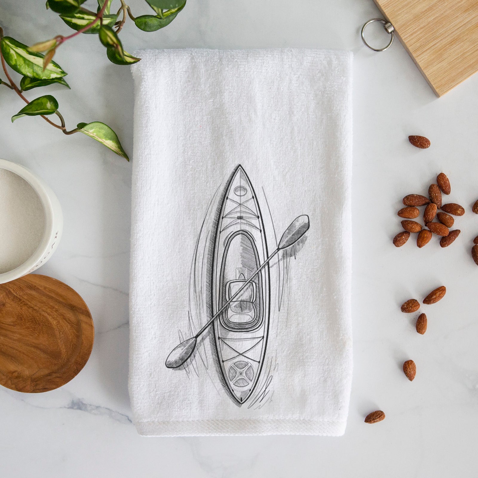 White hand towel printed with a black ink illustration of a kayak with a paddle, seen from above.