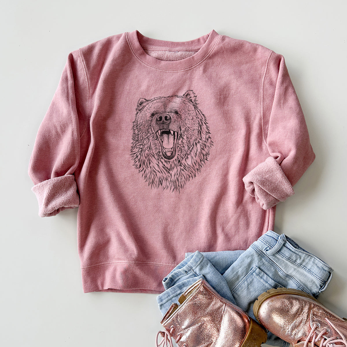Youth crewneck sweatshirt printed with a detailed black ink portrait of a roaring Kodiak bear facing forward, styled flat with jeans and boots.