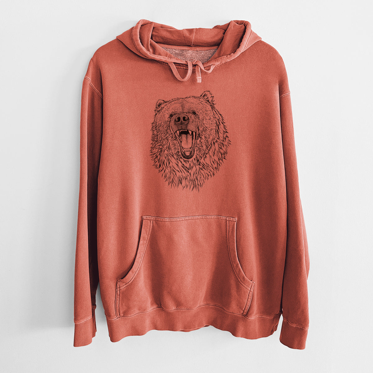 Amber orange pigment dyed hoodie laid flat, printed with a detailed black ink portrait of a roaring Kodiak bear facing forward.