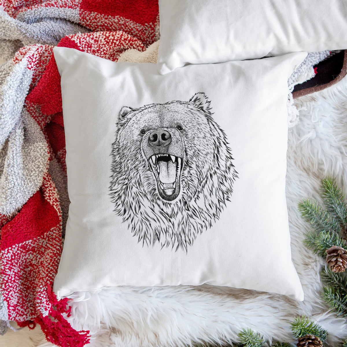 White pillow cover printed with a detailed black ink portrait of a roaring Kodiak bear facing forward, on a woven chair.