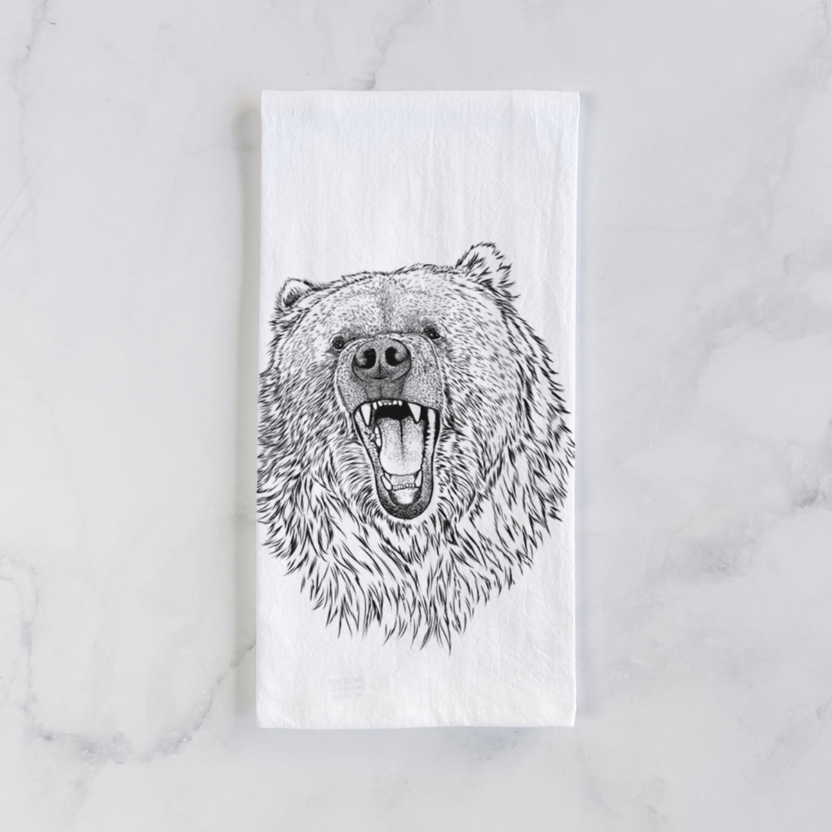 White cotton tea towel laid flat on marble, printed with a detailed black ink portrait of a roaring Kodiak bear facing forward.