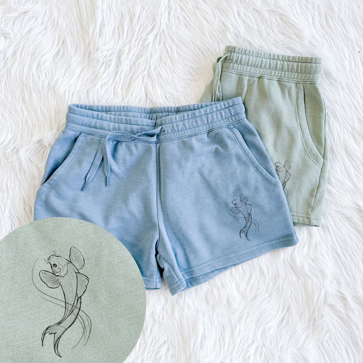 Two pairs of Cali Wave shorts in different colors printed with a black ink line drawing of a koi fish swimming with flowing fins, with a close-up of the print.