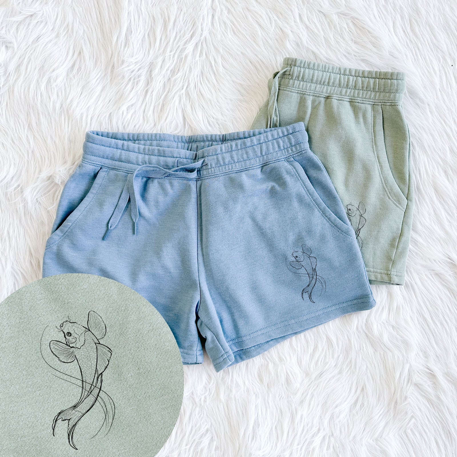 Two pairs of Cali Wave shorts in different colors printed with a black ink line drawing of a koi fish swimming with flowing fins, with a close-up of the print.