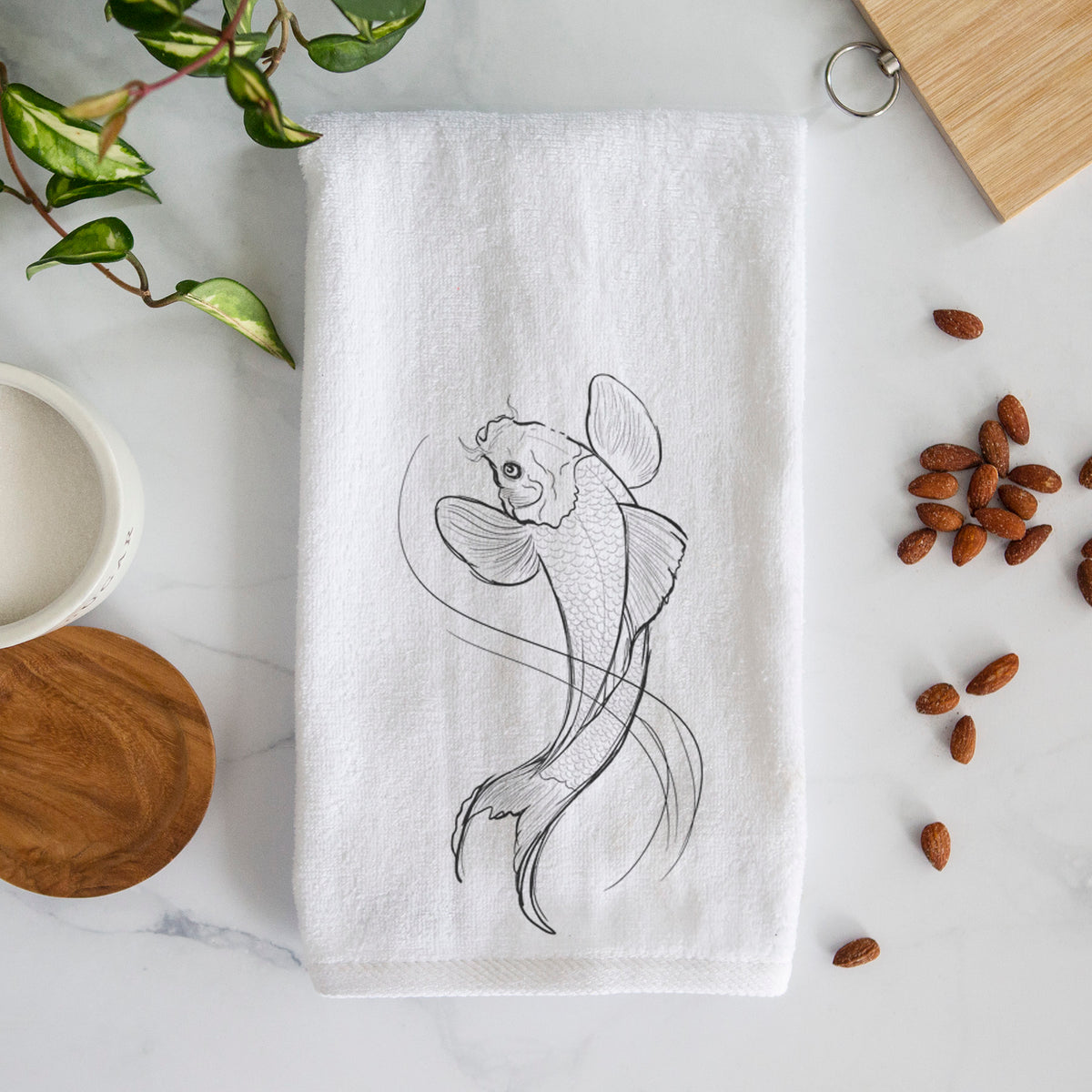 White hand towel printed with a black ink line drawing of a koi fish swimming with flowing fins.