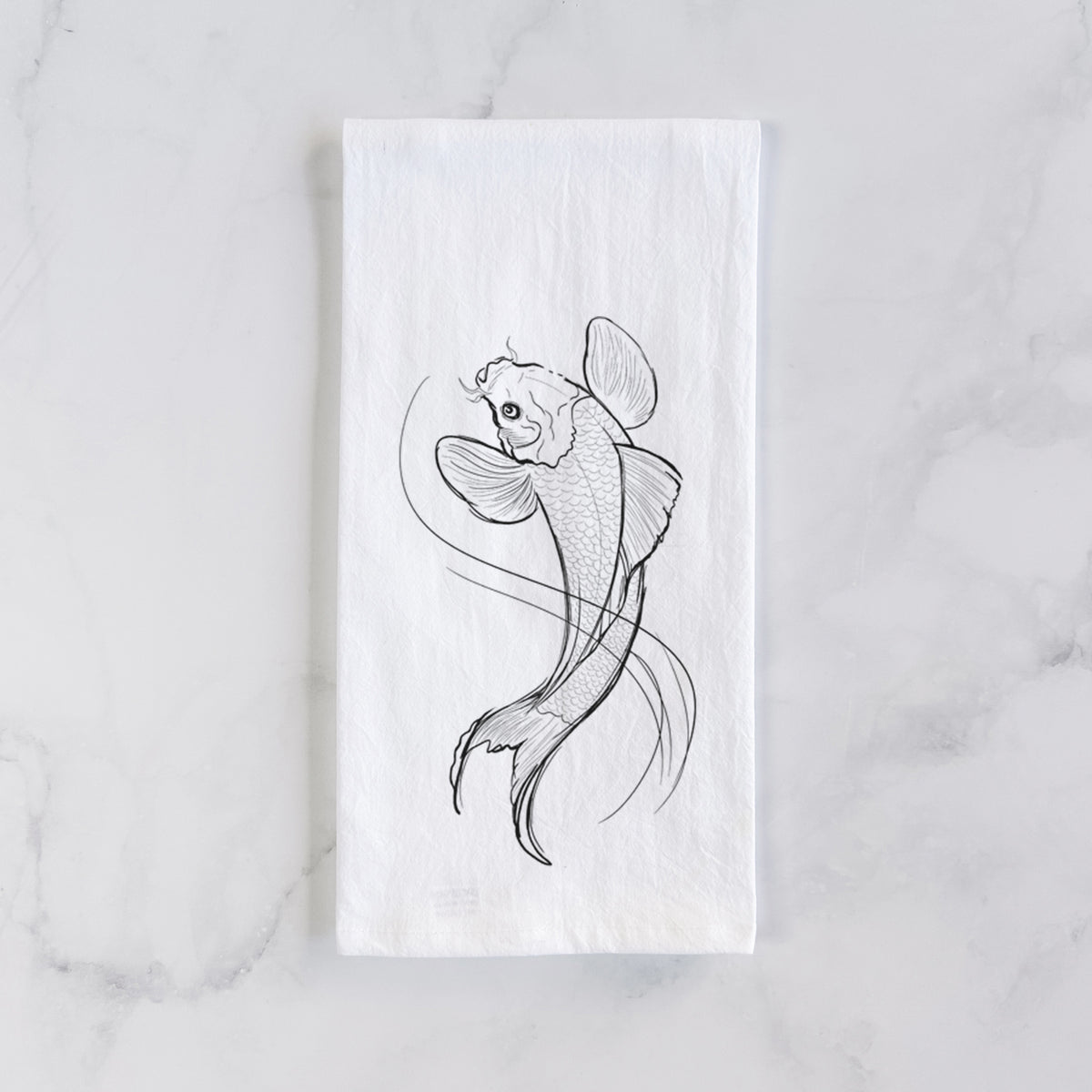 White cotton tea towel laid flat on marble, printed with a black ink line drawing of a koi fish swimming with flowing fins.