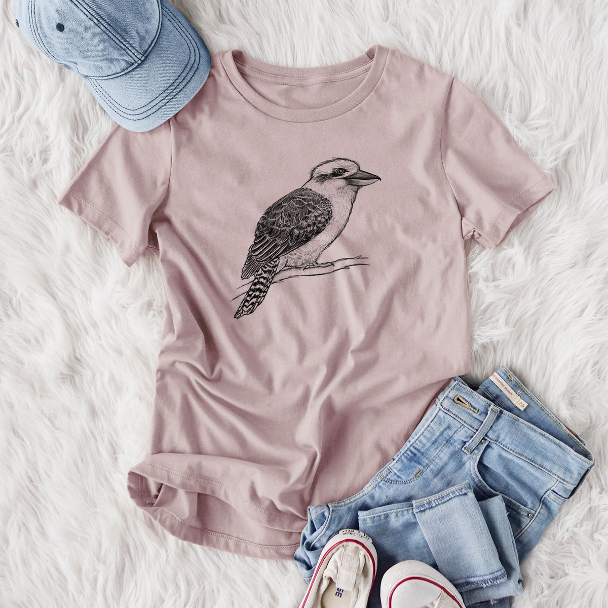 Women's relaxed fit cotton t-shirt printed with a detailed black ink sketch of a kookaburra perched on a branch, styled flat on a white faux fur rug with jeans.
