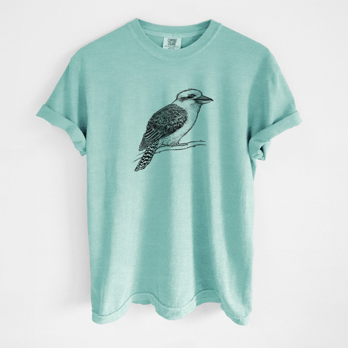 Chalky mint Comfort Colors t-shirt laid flat, printed with a detailed black ink sketch of a kookaburra perched on a branch.