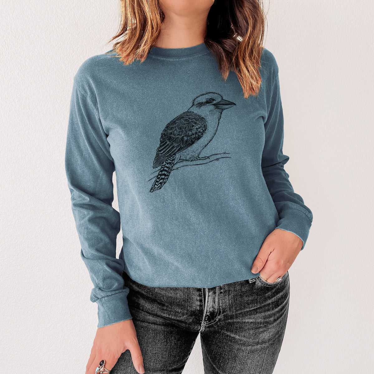 Steel blue Comfort Colors long sleeve shirt printed with a detailed black ink sketch of a kookaburra perched on a branch, shown in a lifestyle photo.