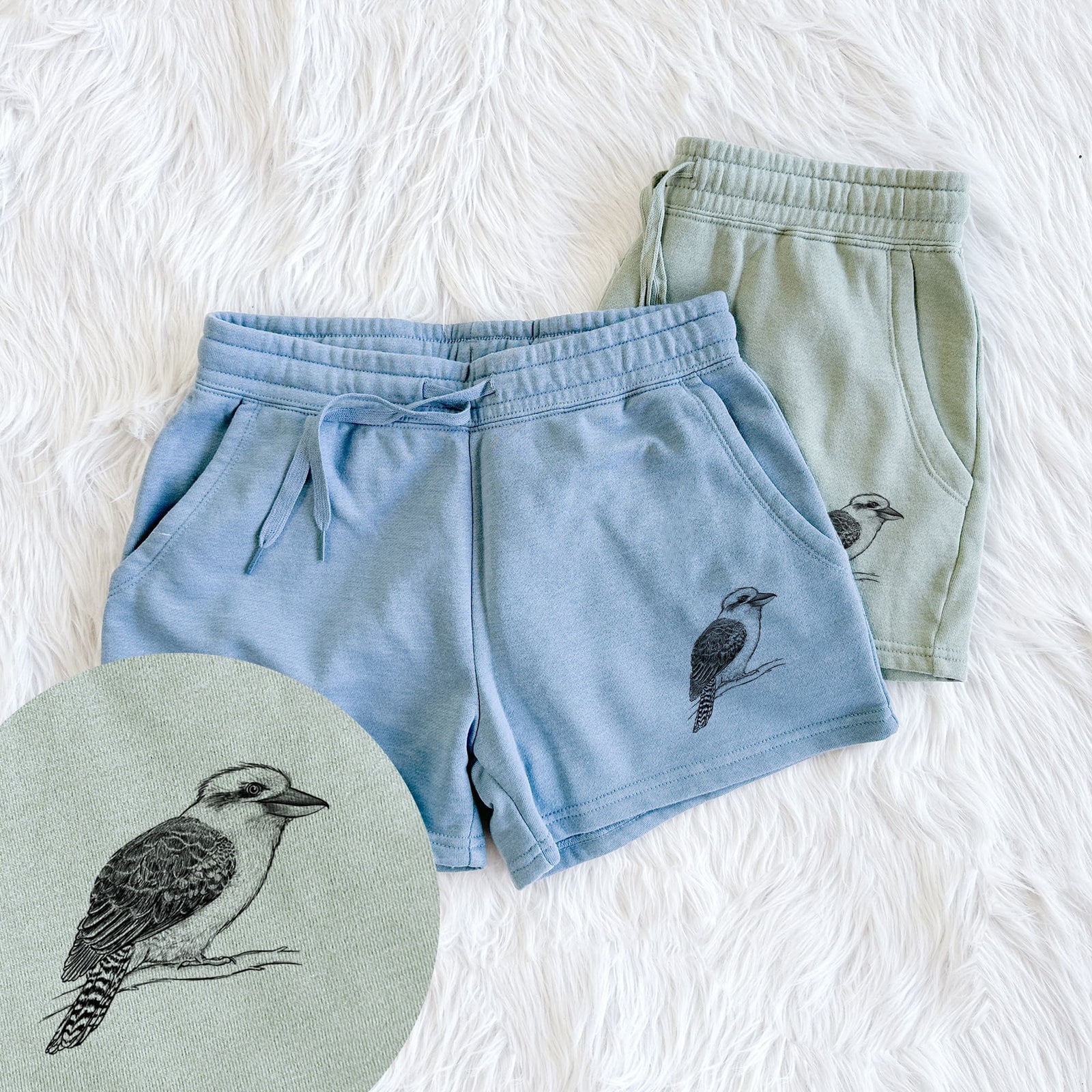 Two pairs of Cali Wave shorts in different colors printed with a detailed black ink sketch of a kookaburra perched on a branch, with a close-up of the print.