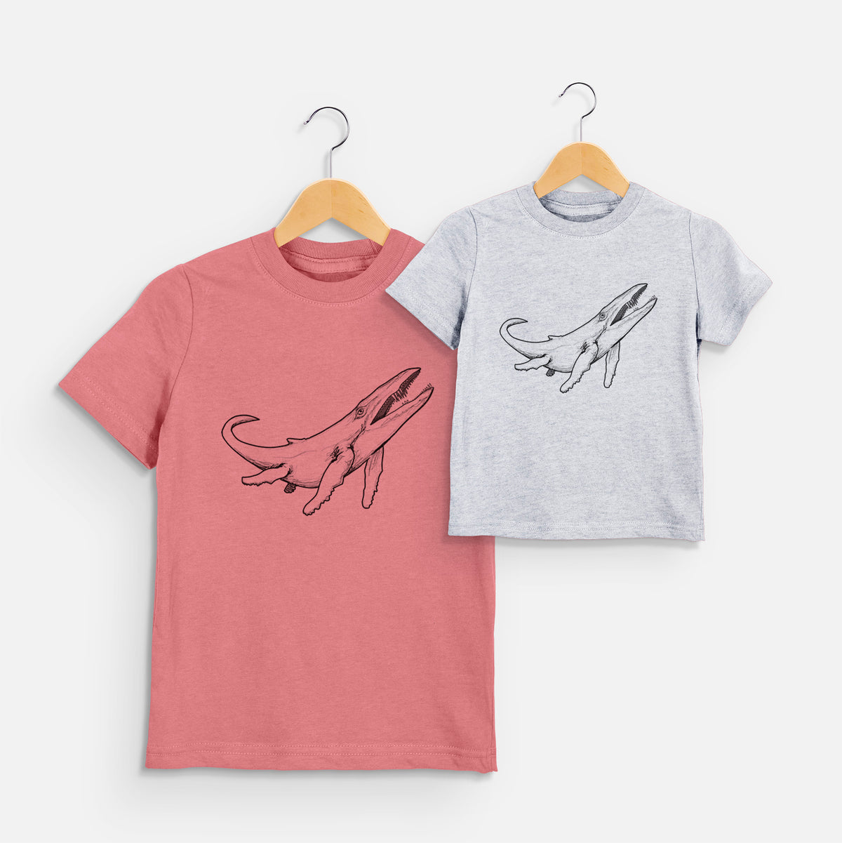 Two youth t-shirts in different colors on hangers, printed with a black ink illustration of a Kronosaurus marine reptile swimming.