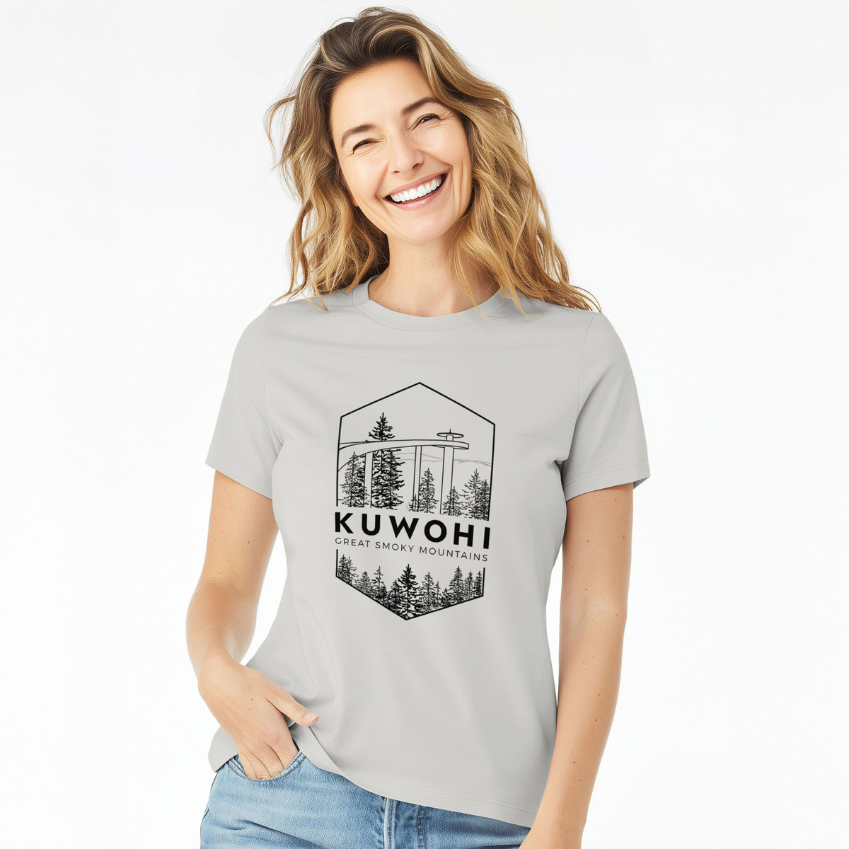Woman wearing a lunar grey women's relaxed fit cotton t-shirt printed with a black line art badge of the Kuwohi observation tower above pine trees, with the words Kuwohi, Great Smoky Mountains.