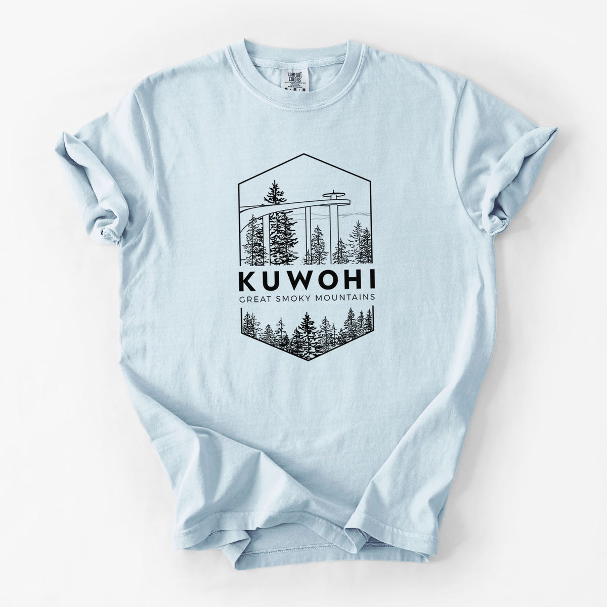 Chambray blue Comfort Colors t-shirt laid flat, printed with a black line art badge of the Kuwohi observation tower above pine trees, with the words Kuwohi, Great Smoky Mountains.