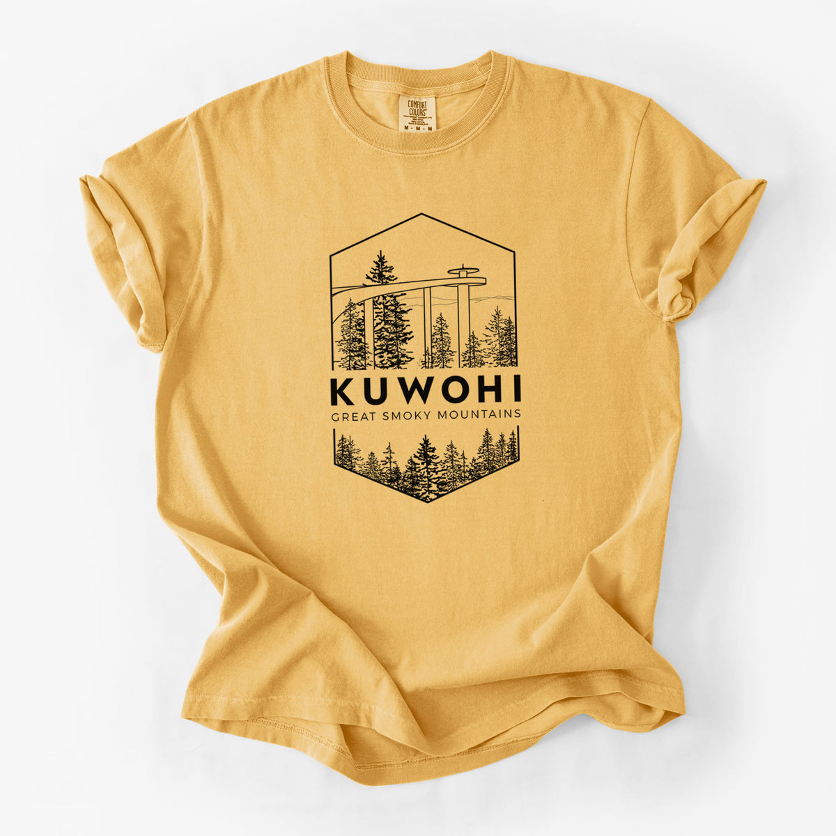 Golden wheat yellow Comfort Colors t-shirt laid flat, printed with a black line art badge of the Kuwohi observation tower above pine trees, with the words Kuwohi, Great Smoky Mountains.