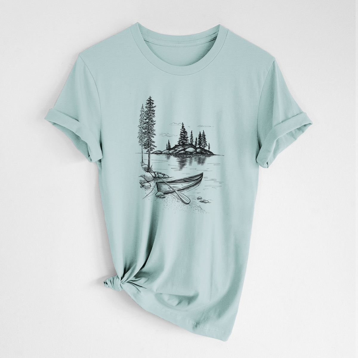 Dusty blue lightweight cotton t-shirt laid flat with the sleeves rolled, printed with a black ink illustration of a canoe resting on the shore of a lake with pine trees on a small island.