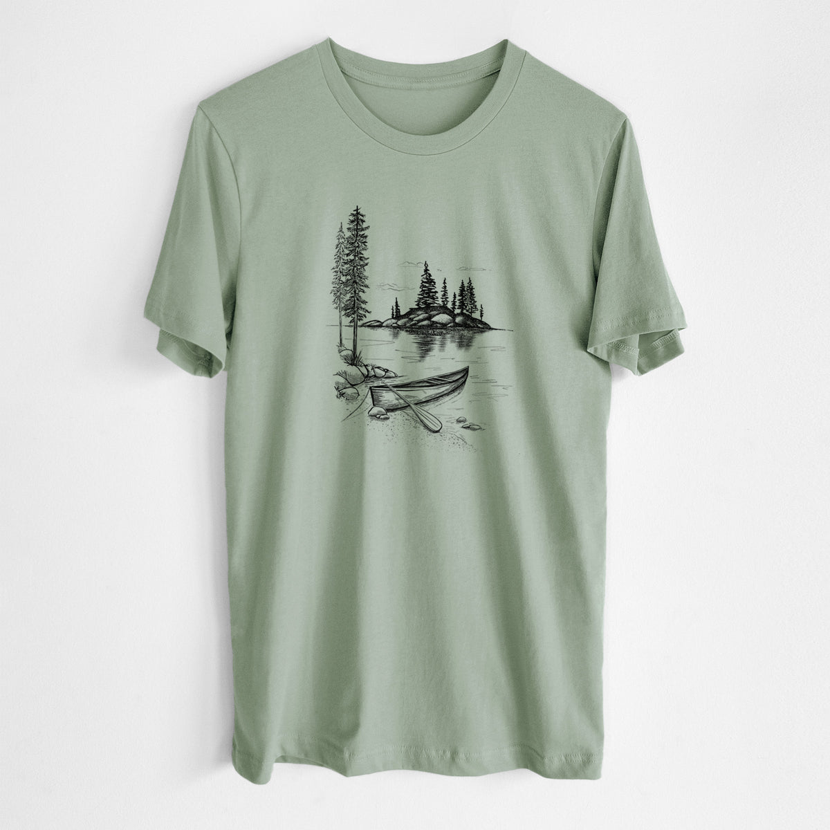 Sage green lightweight cotton t-shirt laid flat, printed with a black ink illustration of a canoe resting on the shore of a lake with pine trees on a small island.