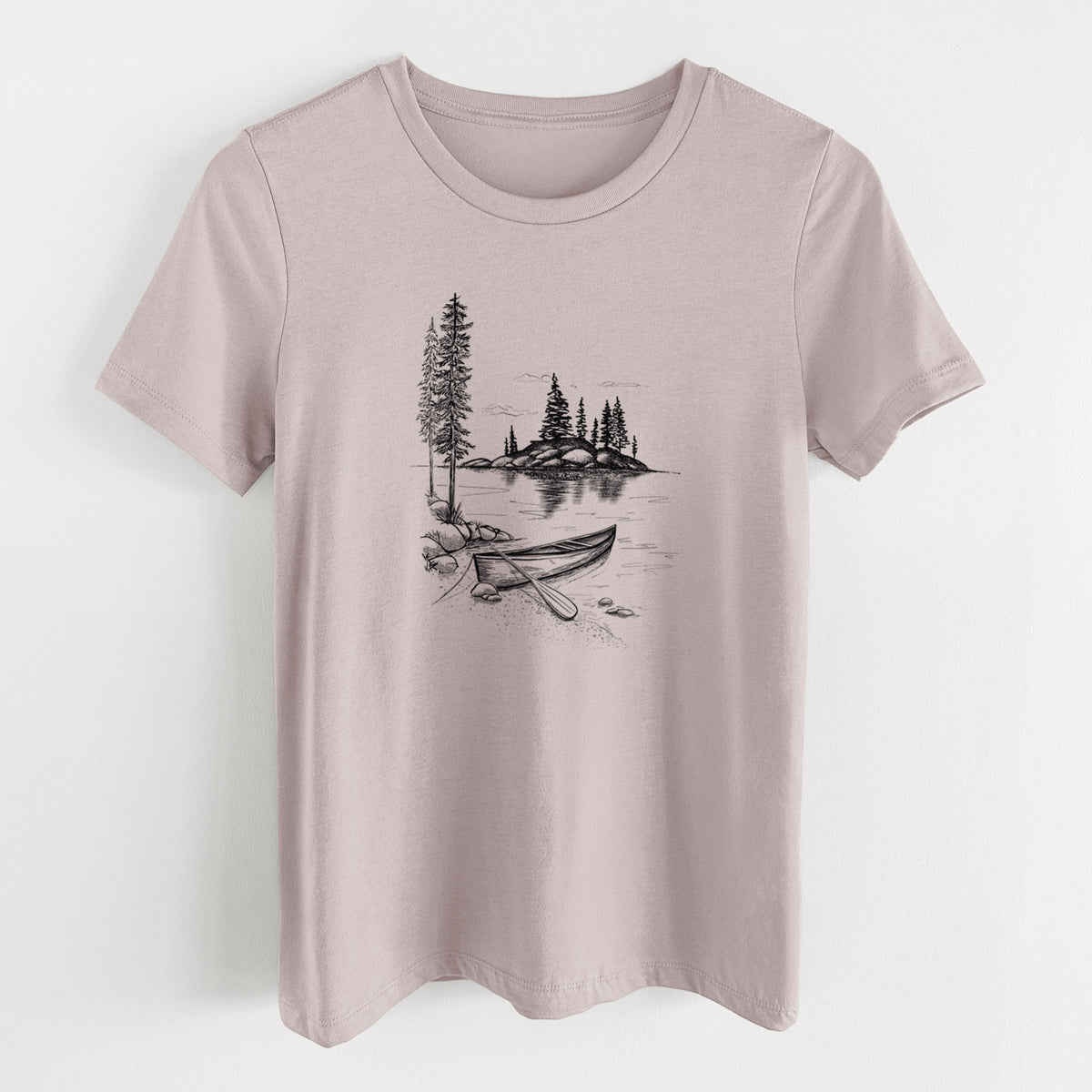 Pink gravel women's relaxed fit cotton t-shirt laid flat, printed with a black ink illustration of a canoe resting on the shore of a lake with pine trees on a small island.