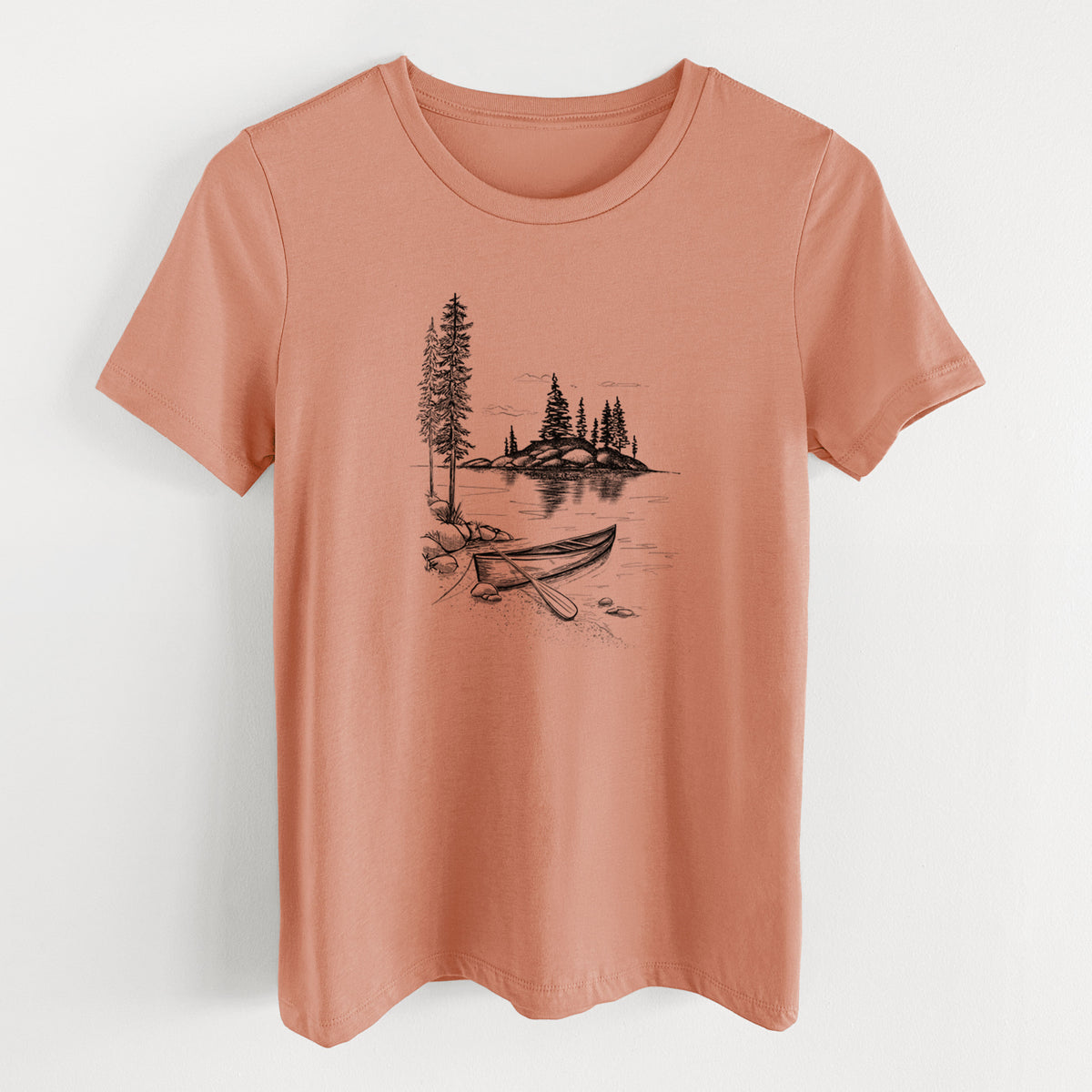 Terracotta orange women's relaxed fit cotton t-shirt laid flat, printed with a black ink illustration of a canoe resting on the shore of a lake with pine trees on a small island.