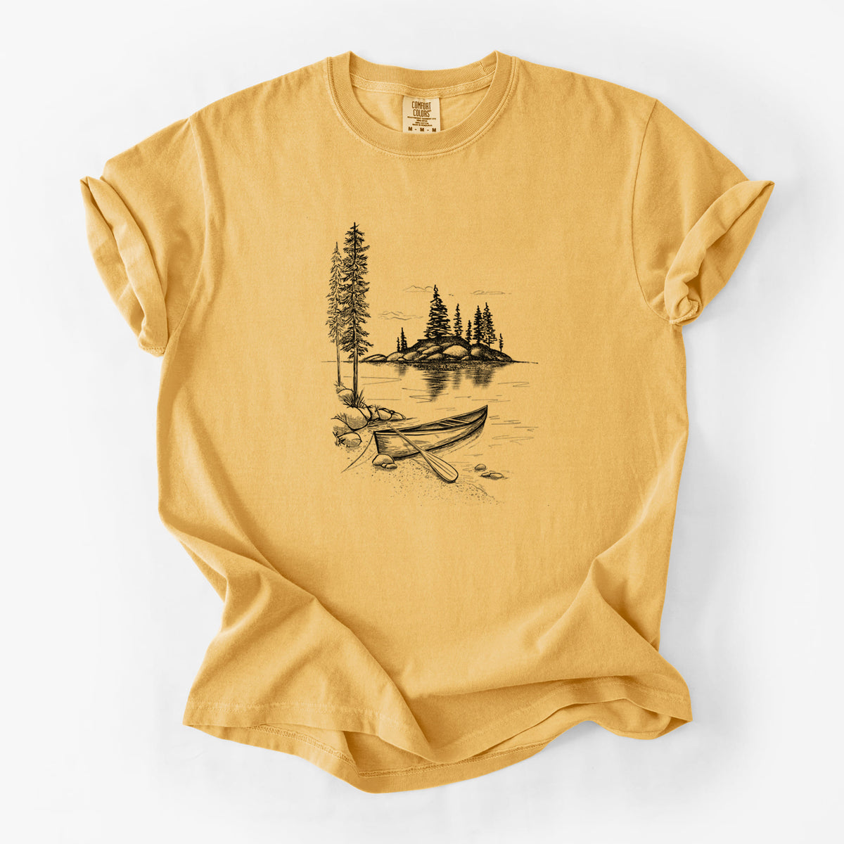 Golden wheat yellow Comfort Colors t-shirt laid flat, printed with a black ink illustration of a canoe resting on the shore of a lake with pine trees on a small island.