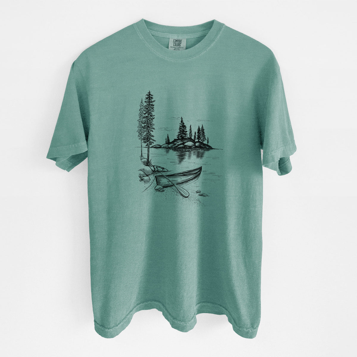 Reef green Comfort Colors t-shirt laid flat, printed with a black ink illustration of a canoe resting on the shore of a lake with pine trees on a small island.
