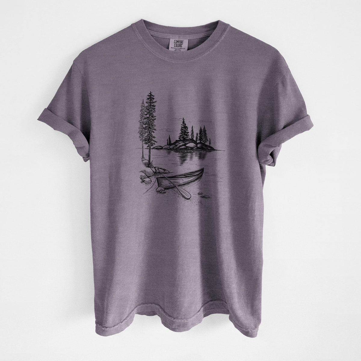 Wine red Comfort Colors t-shirt laid flat, printed with a black ink illustration of a canoe resting on the shore of a lake with pine trees on a small island.