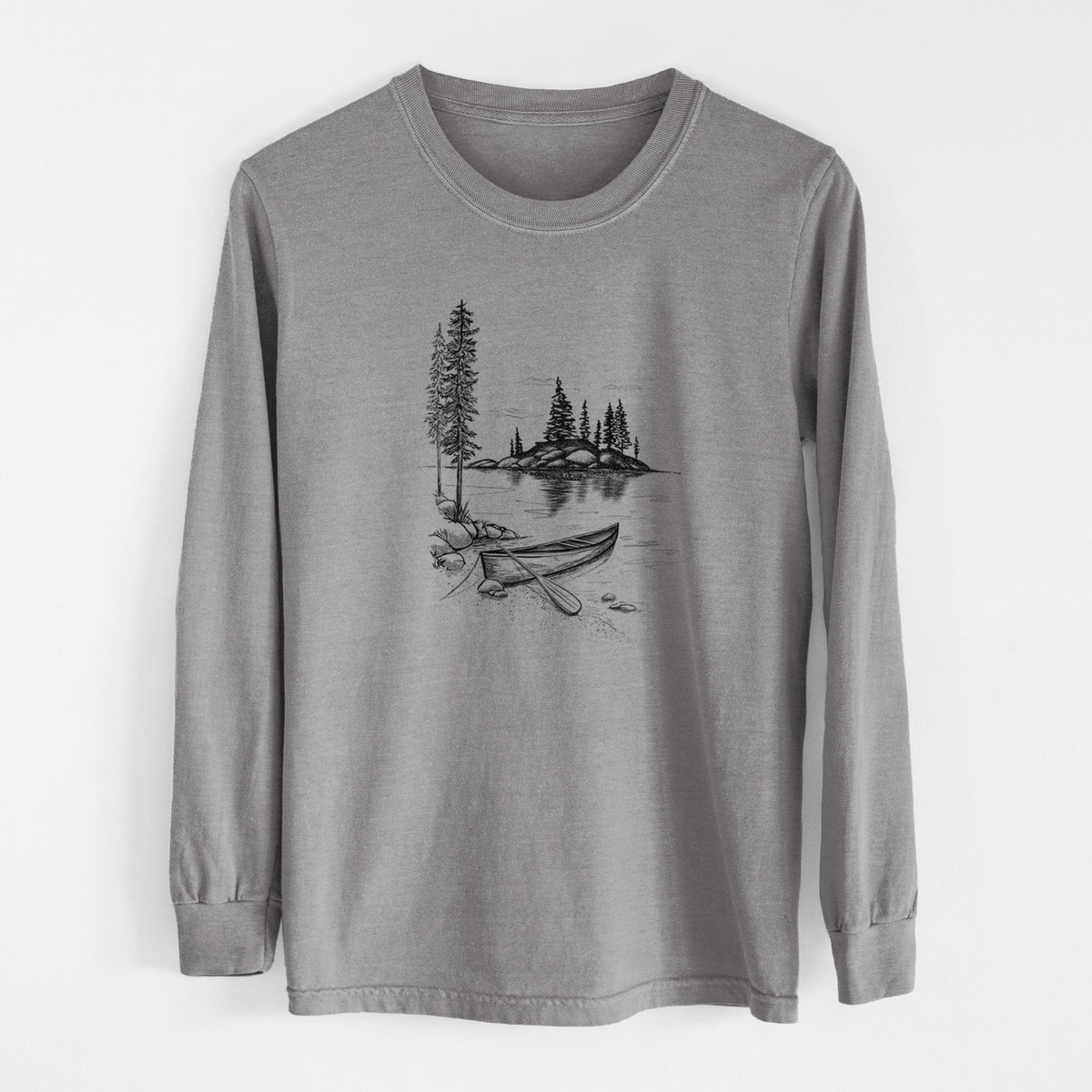 Grey Comfort Colors long sleeve shirt laid flat, printed with a black ink illustration of a canoe resting on the shore of a lake with pine trees on a small island.
