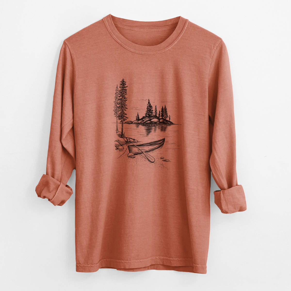 Yam burnt orange Comfort Colors long sleeve shirt laid flat with the cuffs rolled, printed with a black ink illustration of a canoe resting on the shore of a lake with pine trees on a small island.
