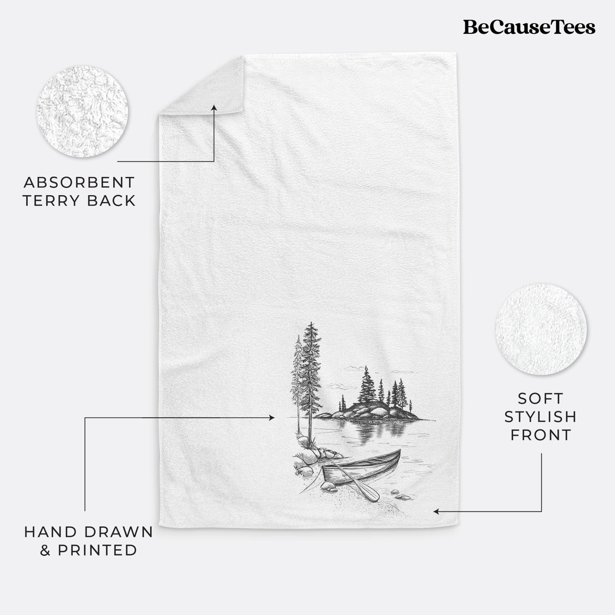 White hand towel printed with a black ink illustration of a canoe resting on the shore of a lake with pine trees on a small island.